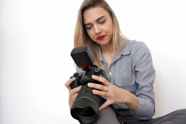 Jovem bela loira segurando uma grande câmera em suas mãos, branco — Fotografia de Stock