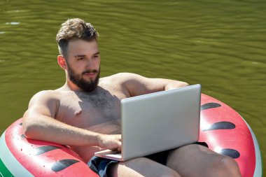 Bir blogcu ya da serbest çalışan mutlu yüzlü bir dizüstü bilgisayara bakar.