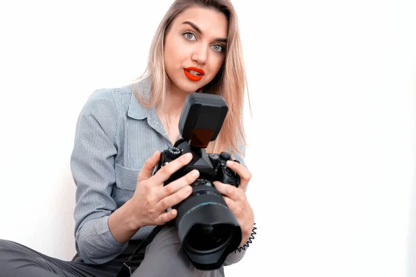 Beautiful young blonde with a big camera looks into the camera — Stock Photo, Image