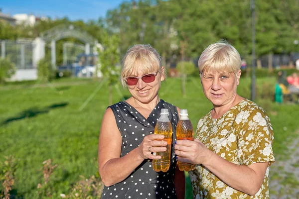 Két idős hölgy átlátszó műanyag sörösüveggel a kezében. — Stock Fotó