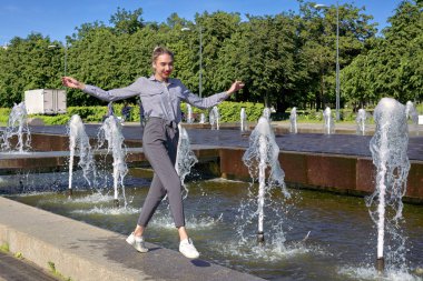 Çeşmenin yanındaki granit kaldırımda çalışan kız. Güneşli.