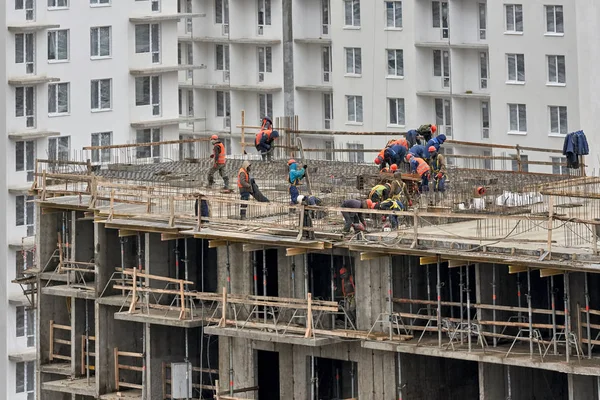 Muchos constructores en cascos y máscaras trabajan en el techo de la b — Foto de Stock