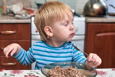 Üç yaşında, kızıl saçlı, kahvaltısını mutfakta yapan bir çocuk. Zevkten gözlerini kapıyor. Kahvaltı için bir çocuğun duyguları.