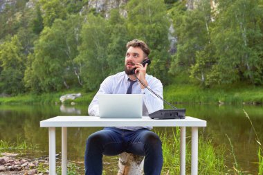 Park 'taki gölün arka planında ofis masasında çalışan genç bir işadamı. Dünyanın herhangi bir yerinden destek