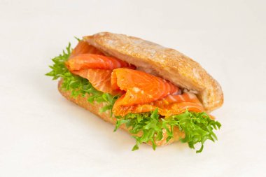 Kırmızı balık somonlu sandviç, Steelhead veya alabalık ve yeşil salata yapraklı. Lezzetli ve sağlıklı fast food. Işık arkaplan üzerinde yakın plan, çapraz çerçeve