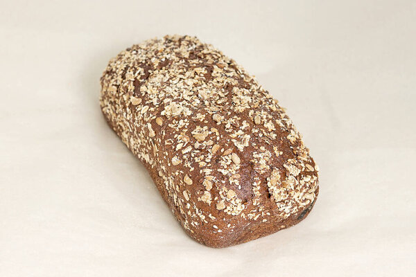 Fresh brown bread from rye flour, sprinkled with sliced almonds. Fresh pastries, a range of bakery and confectionery products. Closeup on a light background, a diagonal position in the frame