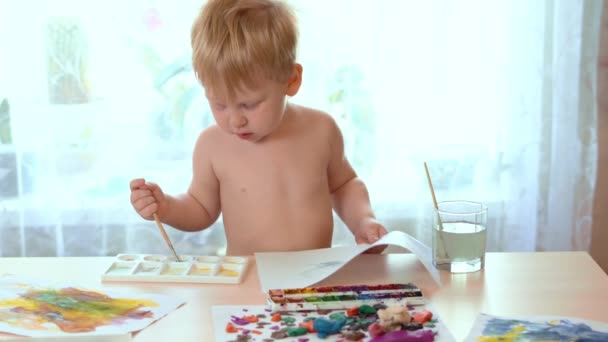 O bebê espirrou e se tornou um pincel para pintar uma folha branca de papel — Vídeo de Stock