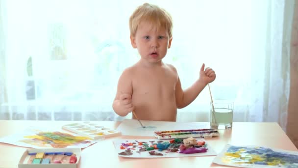 Un niño dibuja con pinturas, la mano de un adulto limpiando dedos manchados niño — Vídeos de Stock