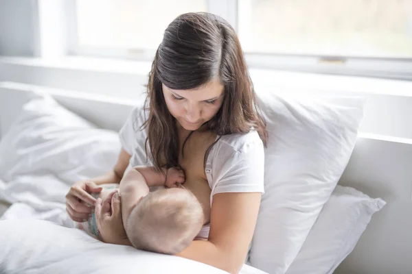 Женщина кормит ребенка на кровати — стоковое фото