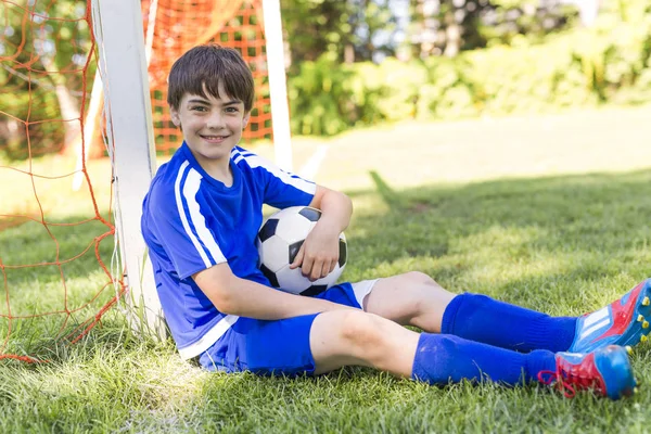 Mladý chlapec s fotbalovým míčem na uniformě sport — Stock fotografie