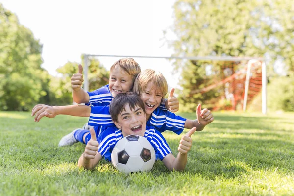 Tiga, anak muda dengan bola sepak pada seragam olahraga — Stok Foto