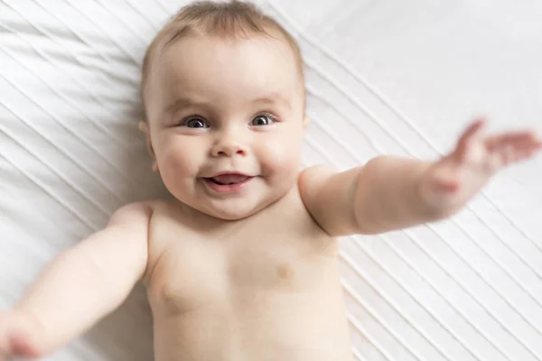 Cute happy 7 month baby girl in diaper lying and playing — Stock Photo, Image