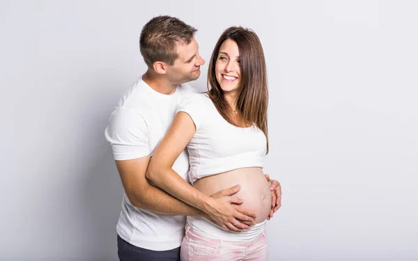 Pareja caucásica esperando bebé sonriendo alegre en blanco — Foto de Stock