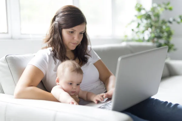 Mor och baby barn funderar på att spela och läsa dator på soffan hemma — Stockfoto