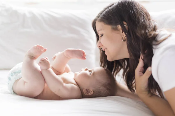 Feliz familia amorosa. Madre jugando con su bebé en el dormitorio. — Foto de Stock