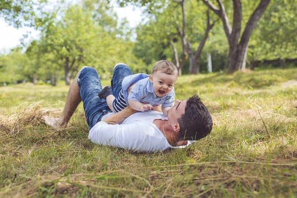 Schöner Vater kleiner Kleinkind Sohn auf der Wiese. — Stockfoto