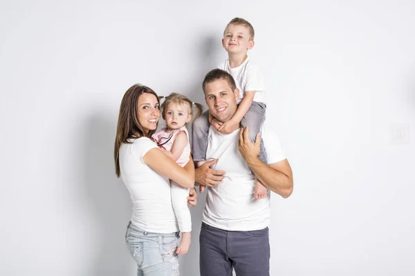 Gelukkig gezin met twee kinderen op studio grijze achtergrond — Stockfoto