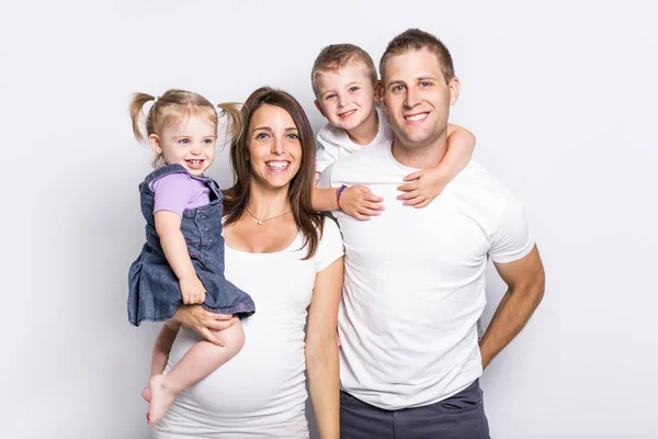 Gelukkig gezin met twee kinderen op studio grijze achtergrond — Stockfoto