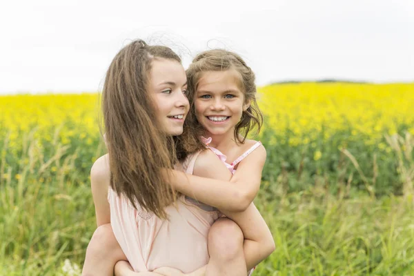Mooie meisjes op een gebied van gele bloemen — Stockfoto