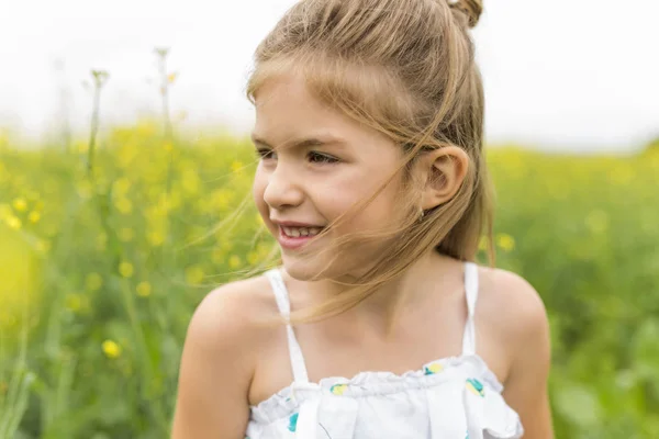 Glad tjej i ett fält av gula blommor — Stockfoto