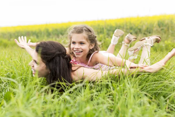 Glückliche Familie Mutter und Kind Tochter Umarmung auf gelben Blumen in der Natur im Sommer — Stockfoto