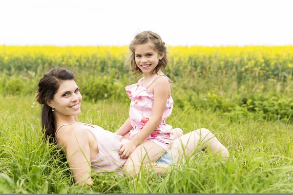 Glückliche Familie Mutter und Kind Tochter Umarmung auf gelben Blumen in der Natur im Sommer — Stockfoto