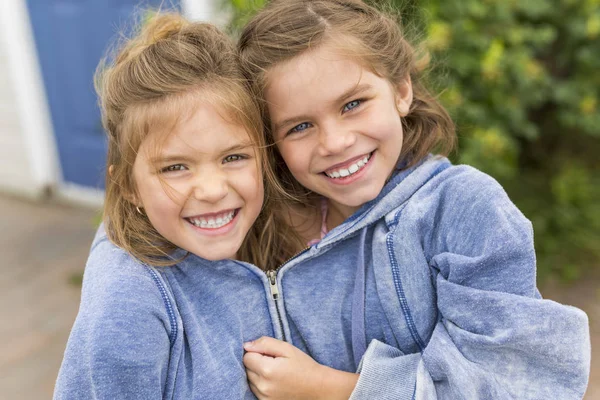 Gelukkig zusters op het strand met de dezelfde hoodies — Stockfoto