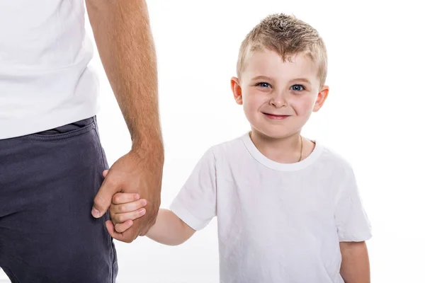 Boy holding hands of his father standing against white background. — Stock Photo, Image