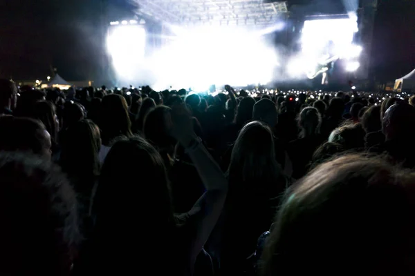 Siluetas de la multitud de conciertos frente a las luces del escenario brillantes. Fondo oscuro, humo, proyectores de conciertos — Foto de Stock