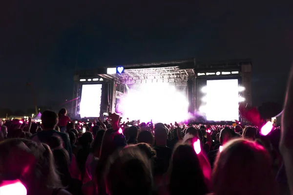 Siluetas de la multitud de conciertos frente a las luces del escenario brillantes. Fondo oscuro, humo, proyectores de conciertos — Foto de Stock