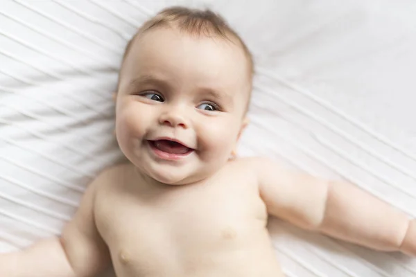 Bonito feliz 7 meses bebê menina na fralda mentindo e jogando — Fotografia de Stock