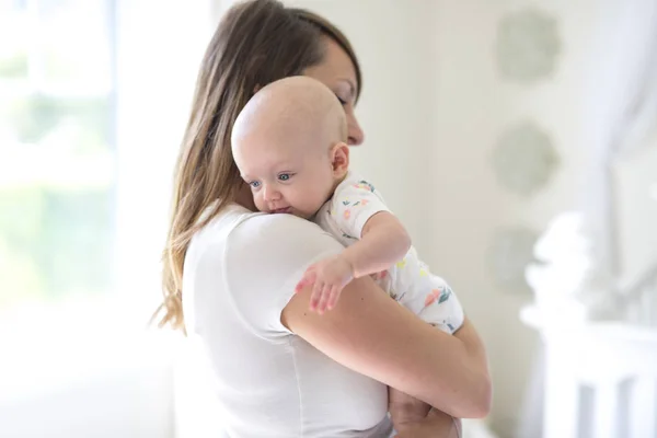 Ung mamma håller sitt nyfödda barn i baby rummet — Stockfoto