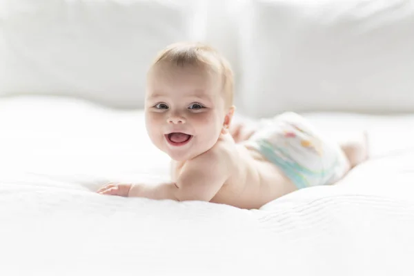 Linda niña feliz de 7 meses en pañal mintiendo y jugando — Foto de Stock