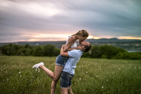 年轻夫妇享受日落在草地上 — 图库照片