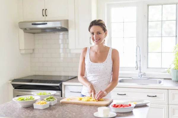 Mulher linda fazendo uma salada em sua cozinha — Fotografia de Stock