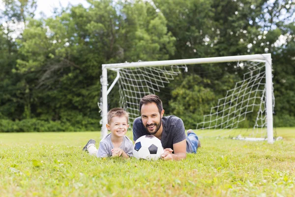 Jovem pai com seu filhinho jogando futebol em campo de futebol — Fotografia de Stock