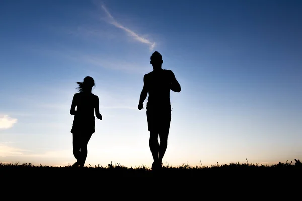 在日出的慢跑者夫妇的剪影 — 图库照片