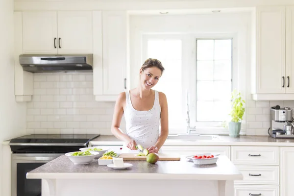 Mulher linda fazendo uma salada em sua cozinha — Fotografia de Stock