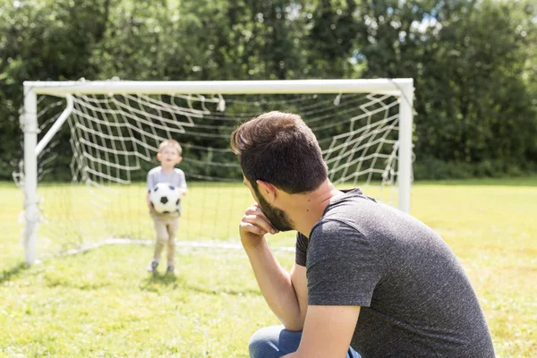 Ung far med sin lille son spelar fotboll på fotbollsplan — Stockfoto
