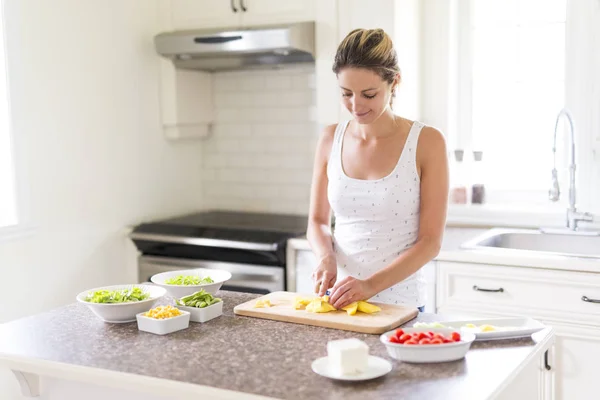 Mulher linda fazendo uma salada em sua cozinha — Fotografia de Stock