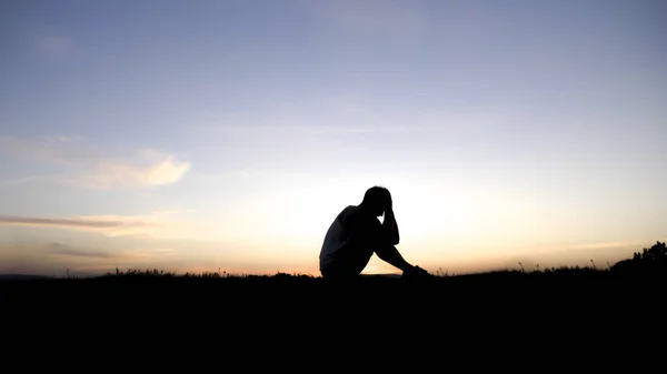 Triste joven silueta preocupado al atardecer —  Fotos de Stock