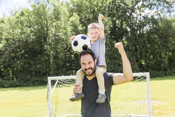 Giovane padre con il suo piccolo figlio che gioca a calcio sul campo da calcio — Foto Stock