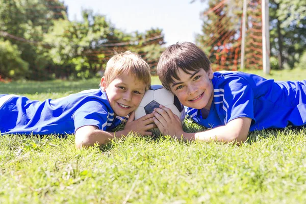 Два мальчика с футбольным мячом в спортивной форме — стоковое фото