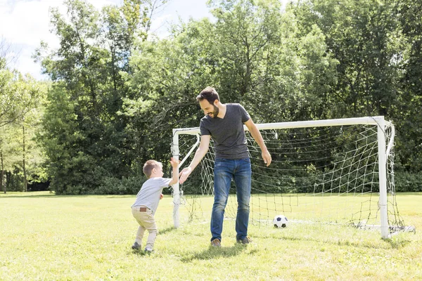 Young father with his little son playing football on football pitch — Stock Photo, Image