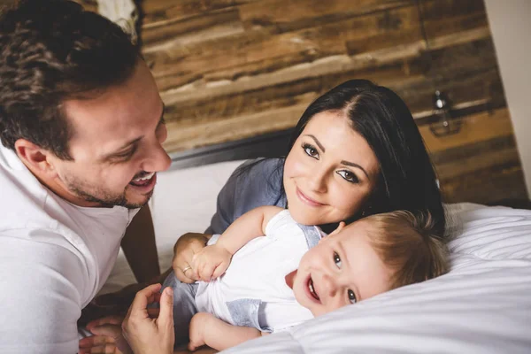 Los padres cariñosos con su lindo niño en la cama — Foto de Stock