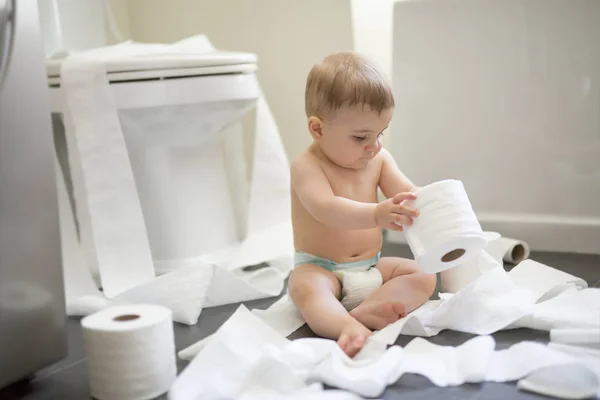 Peuter scheurt wc-papier in de badkamer — Stockfoto