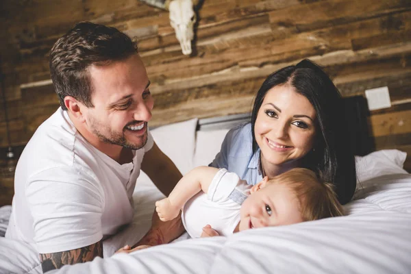 Szerető szülők saját aranyos kisfiú ágyon — Stock Fotó