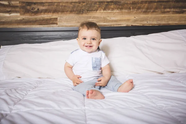 Niedlicher kleiner Junge in weißer Bettwäsche. — Stockfoto