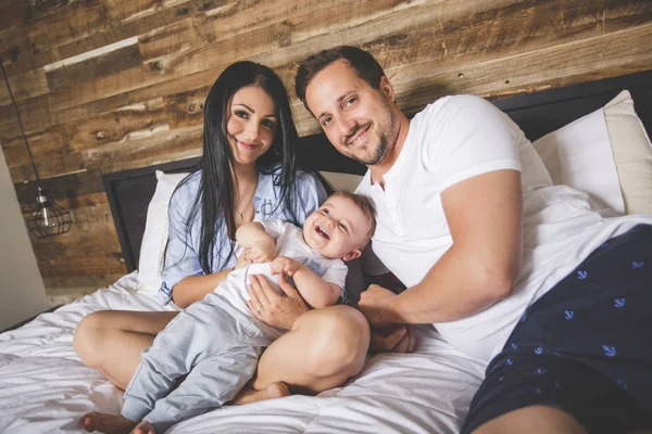 Loving parents with their cute little boy on bed — Stock Photo, Image