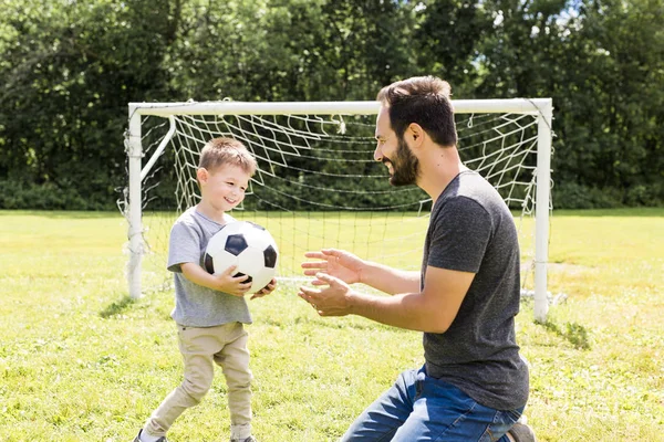 Jonge vader met zijn zoontje voetballen op voetbalveld — Stockfoto